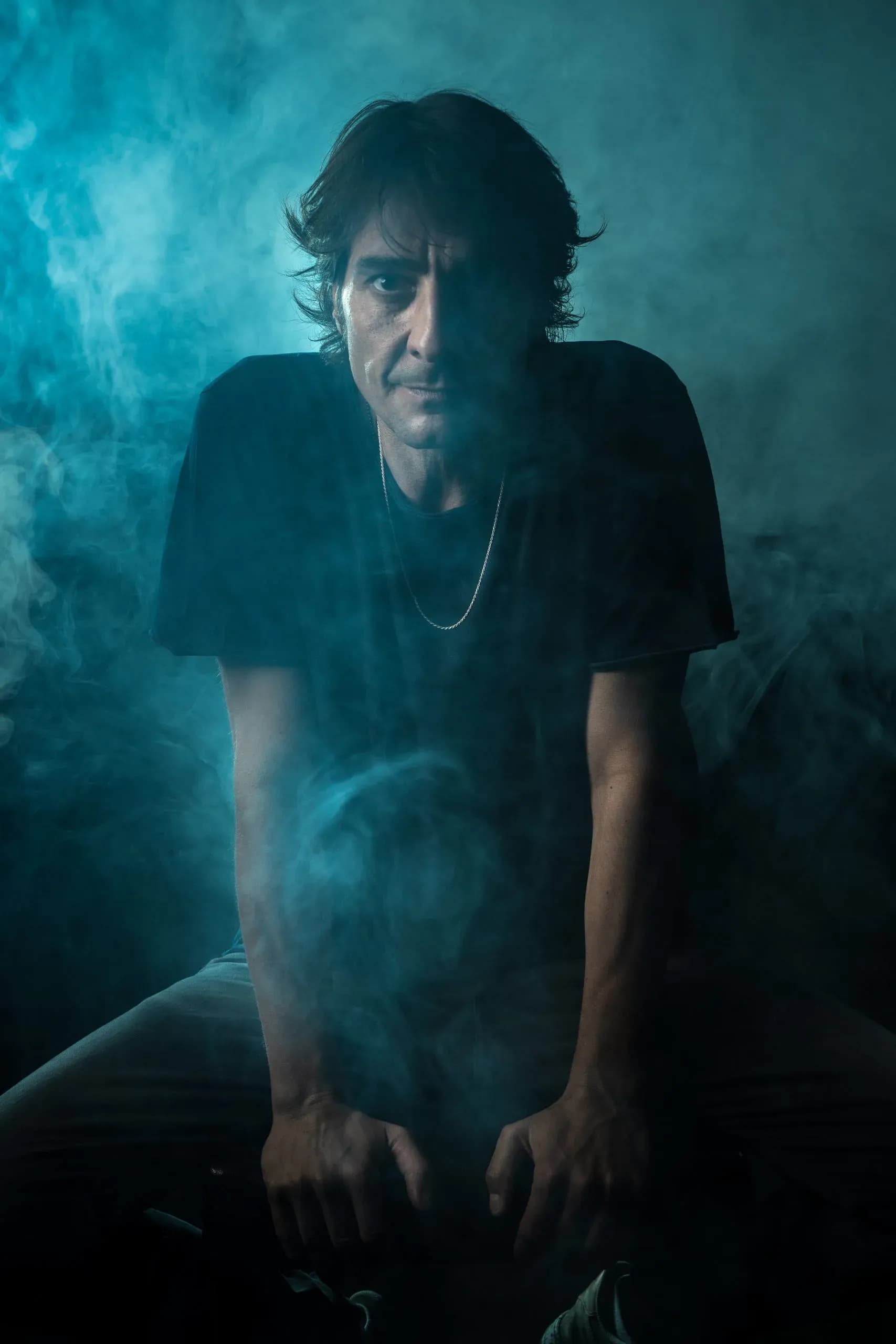 Retrato de Abel Almena rodeado de humo azul en sesión de estudio, DJ con 30 años de trayectoria y residente en Pacha