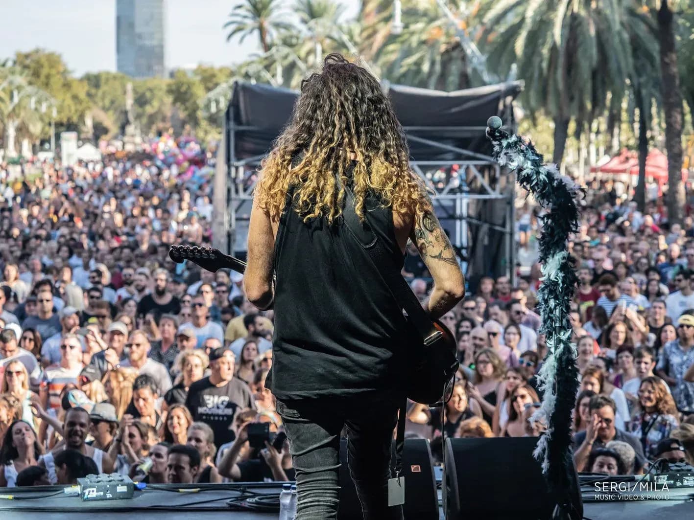 Guitarrista de Big Mouthers de espaldas tocando frente a una multitud enorme en un concierto al aire libre en Barcelona
