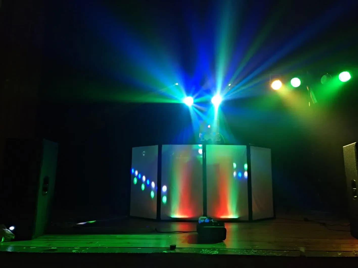 Cabina de discomovil con biombos blancos y focos LED proyectando rayos azules y verdes en sala oscura
