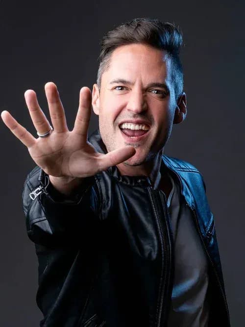 DJ Iván Jiménez en chaqueta de cuero negra extendiendo la mano abierta a cámara, retrato de estudio sobre fondo gris