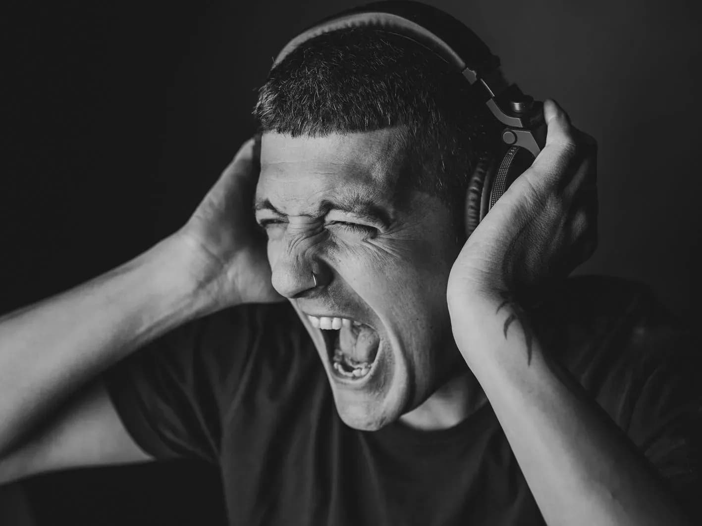 Pablo Picón gritando con auriculares puestos sujetándose la cabeza en retrato dramático en blanco y negro de estudio