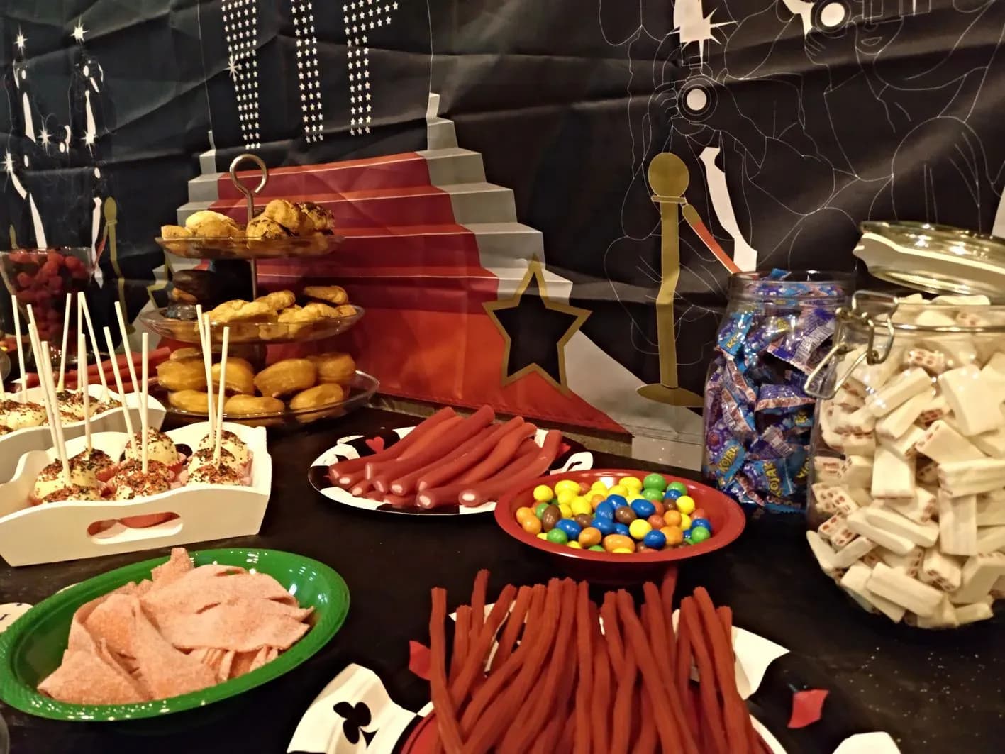 Mesa de chuches y snacks para fiesta infantil con conos rojos, gominolas, patatas fritas y caramelos