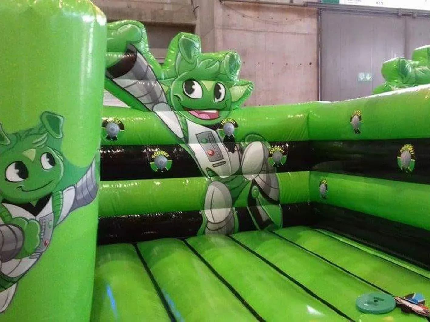 Hinchable infantil verde con figuras de monstruitos y ventanas redondas en formato cuadrilátero, modelo deportivo