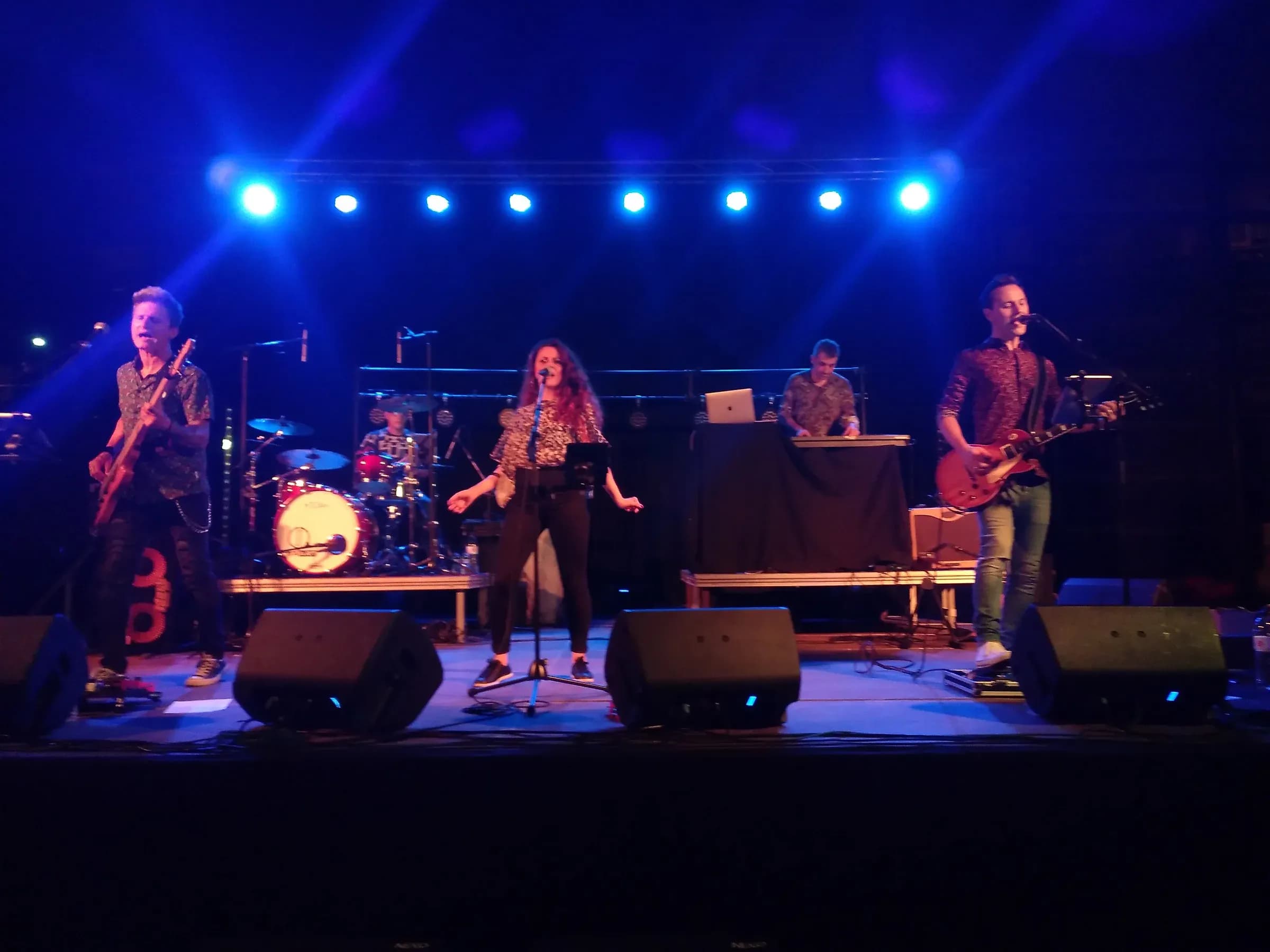 Mind Trick tocando en directo con vocalista guitarras y bateria bajo focos azules