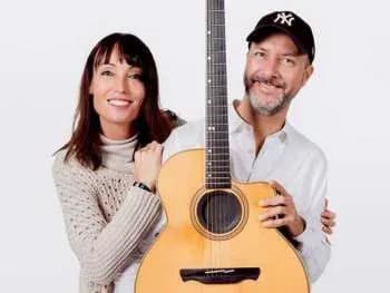 Míriam Hernández y guitarrista con gorra NY abrazados junto a guitarra acústica, retrato del dúo acústico de Miris Way
