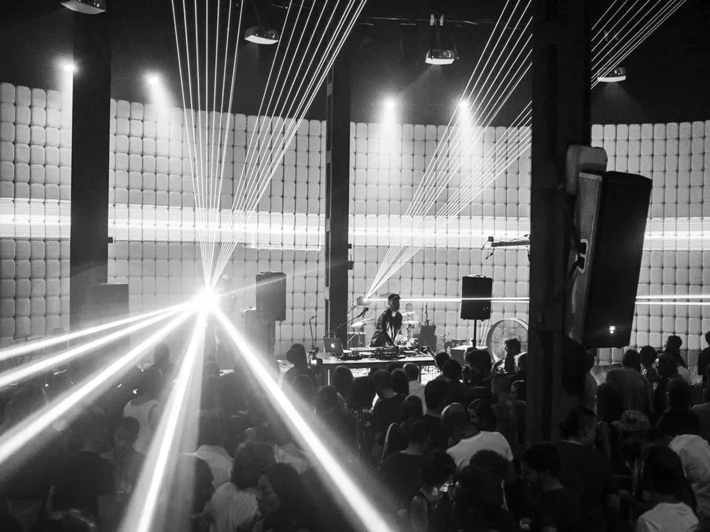 Cabina de Resonance entre múltiples haces de luz láser cruzando una nave de paneles acústicos llena de público
