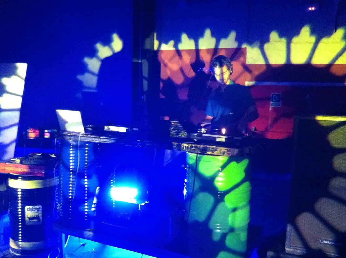 Tecnico de sonido en mesa de mezclas en fiesta al aire libre con banda actuando bajo porche iluminado en azul