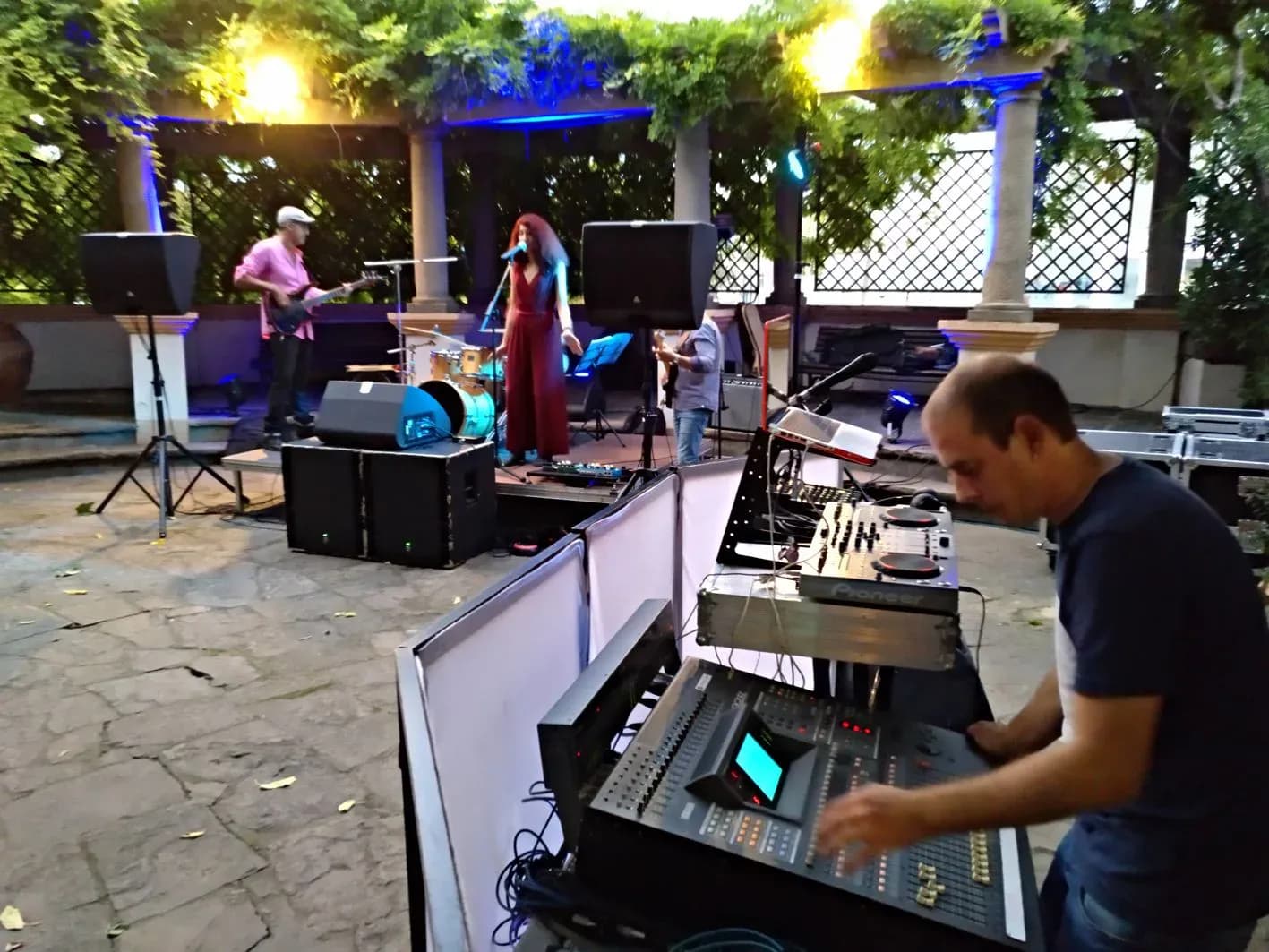 Cabina de sonorizacion e iluminacion con DJ tras pantallas blancas iluminadas en azul y proyecciones graficas