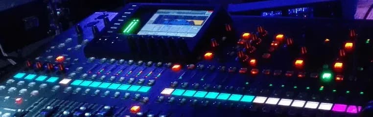 Detalle de la mesa de mezclas digital con faders iluminados durante un evento en directo