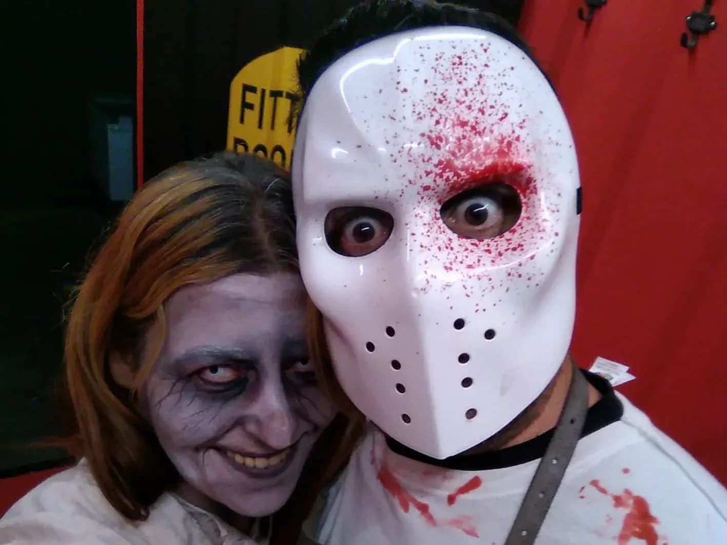 Pareja con maquillaje zombi y máscara estilo Jason ensangrentada posando juntos en photocall de Túnel del Terror