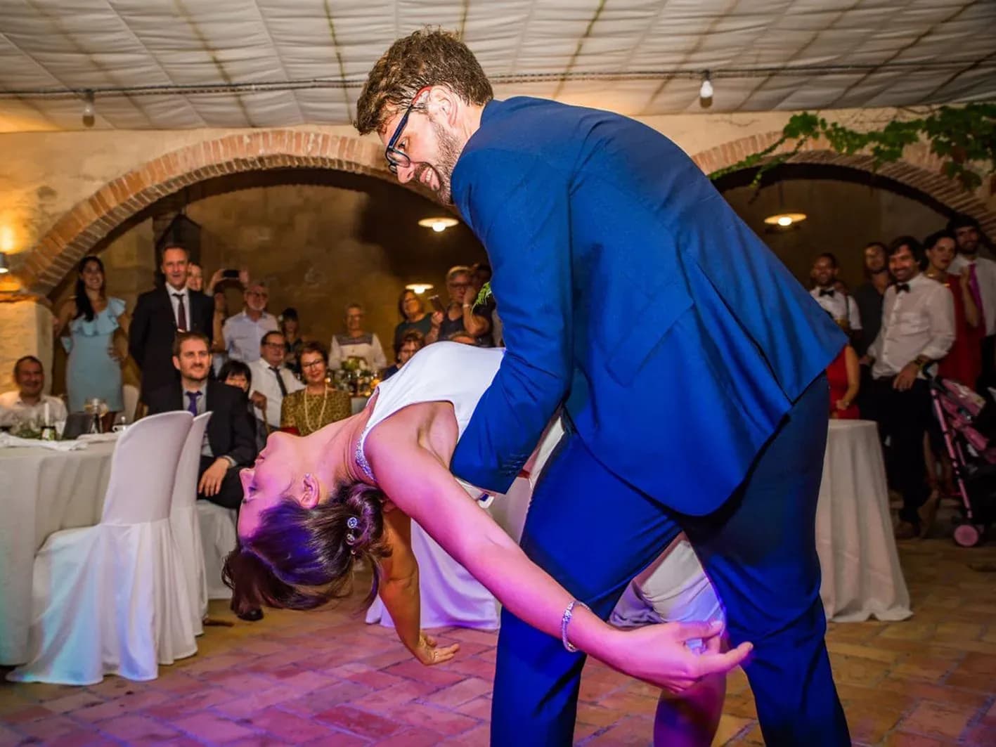 Novios bailando el primer baile con el novio inclinando a la novia ante los invitados aplaudiendo