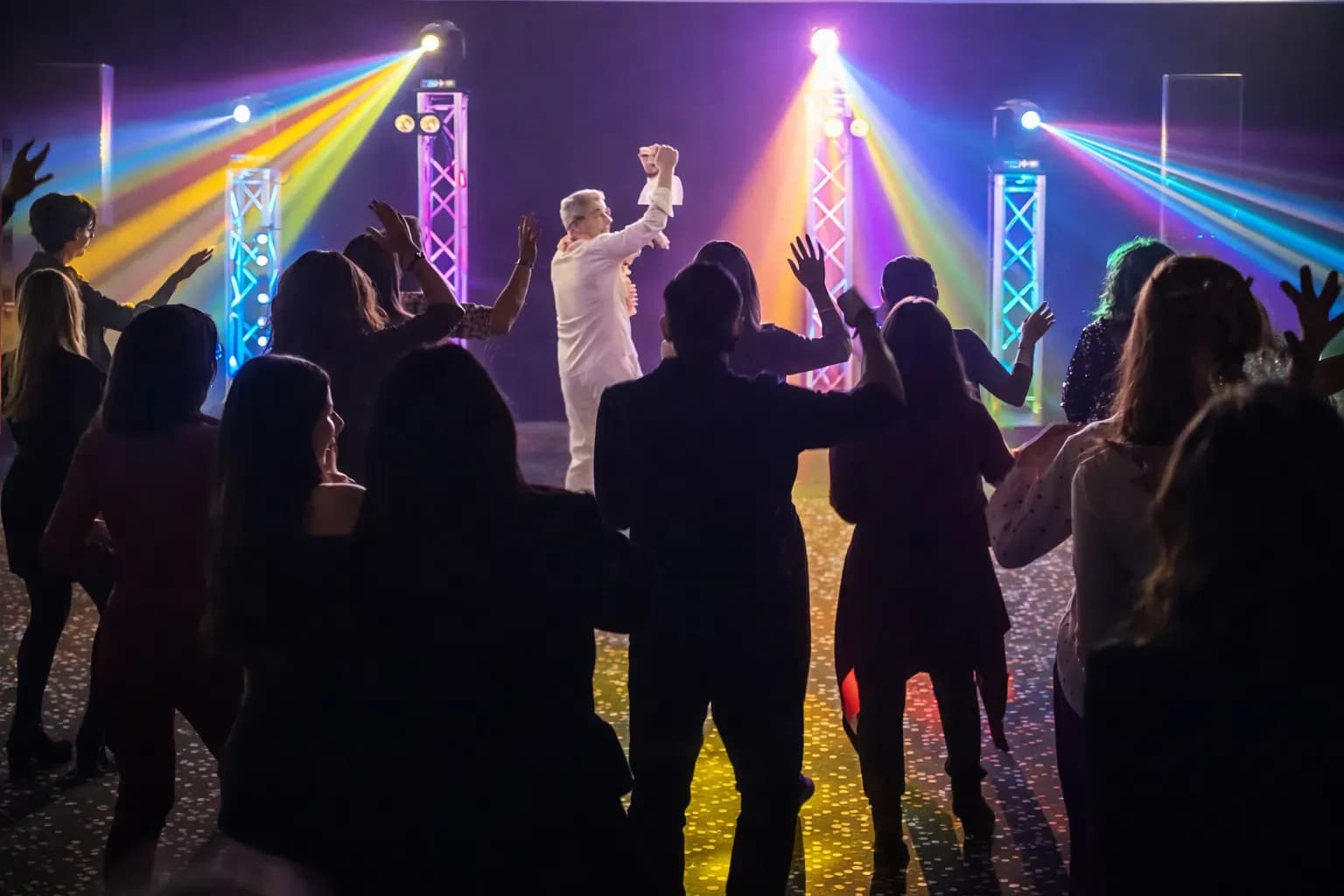 Cabina de discomóvil con altavoces, foco luminoso multicolor y vallas blancas iluminadas en sala con suelo de madera